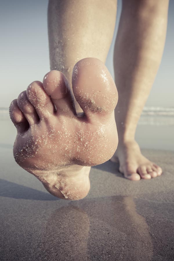 Planta del pie de persona andando por la playa